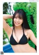 A woman in a black bikini posing by a pool.