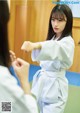 A woman in a white kimono is practicing karate. 