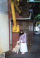 A woman standing next to a dog on a sidewalk.