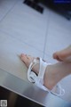 A woman's feet with a pair of white lace sandals on a counter.