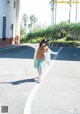 A woman walking down a street with her arms outstretched.