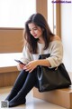 A woman sitting on a bench looking at her phone.