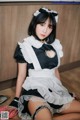 A woman dressed as a maid sitting on the floor.