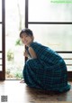 A woman in a blue and black plaid dress sitting on the floor.