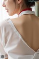 A woman wearing a white blouse with a red collar.