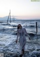 A woman in a white dress standing in the ocean.