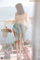 A woman standing on a balcony looking out over the ocean.