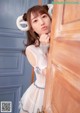 A woman in a white dress leaning against a door.