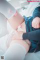 A woman in white stockings and a blue sweater is laying on a bed.